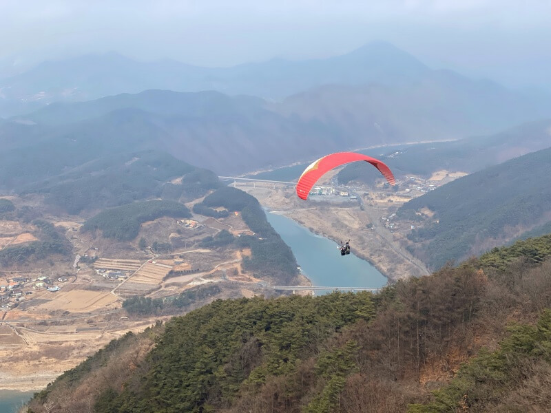 단양에서 패러글라이딩을 하는 사람들 아래 강이 보임